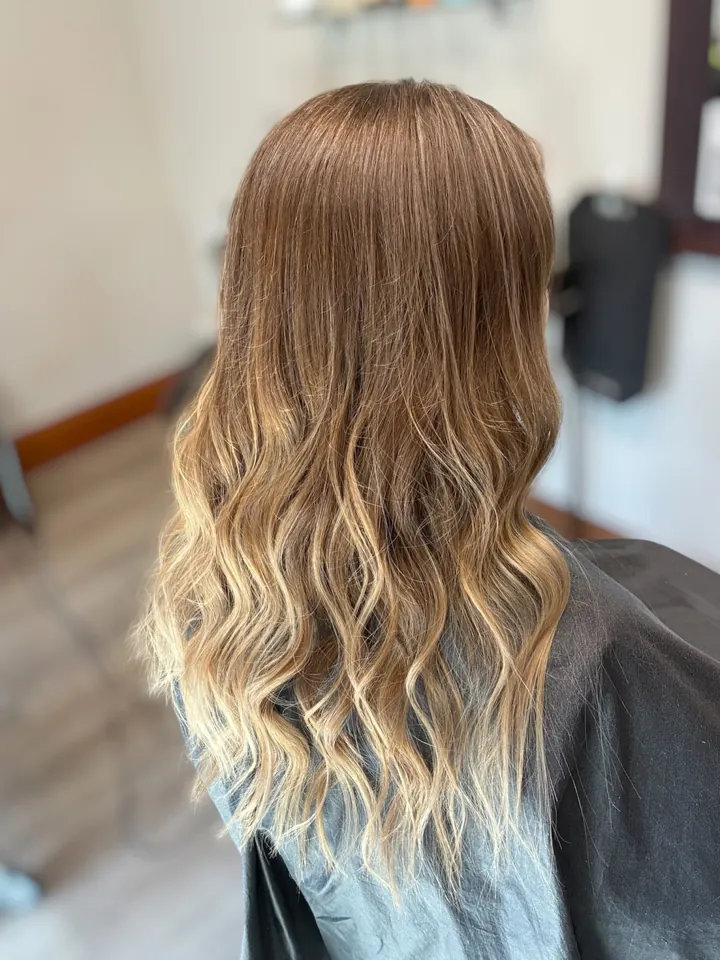 Back view of long, soft waves blending from light brown to blonde, finished in the salon